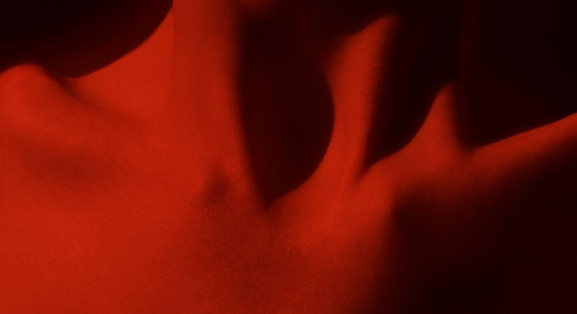Close up of woman's clavicle with red light reflecting off the body