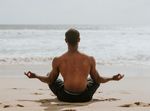 man meditating on the beach