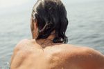 A man with wet hair looking outward over the water