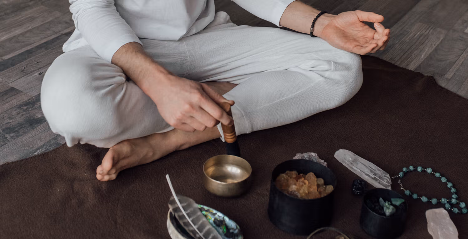 Cross-legged person sits with bowls on the floor in front of them.