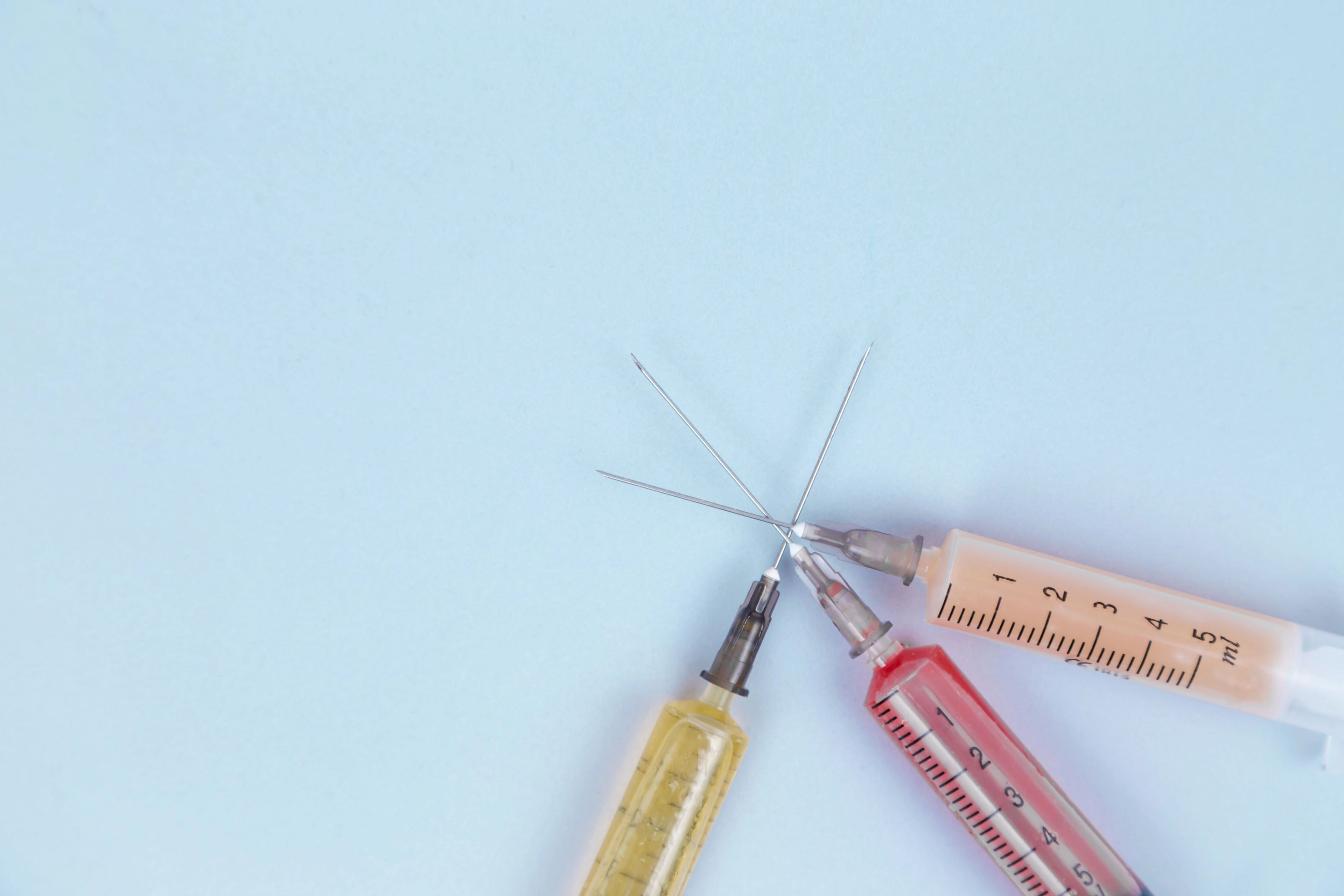 Three syringes with different colored liquids overlap.