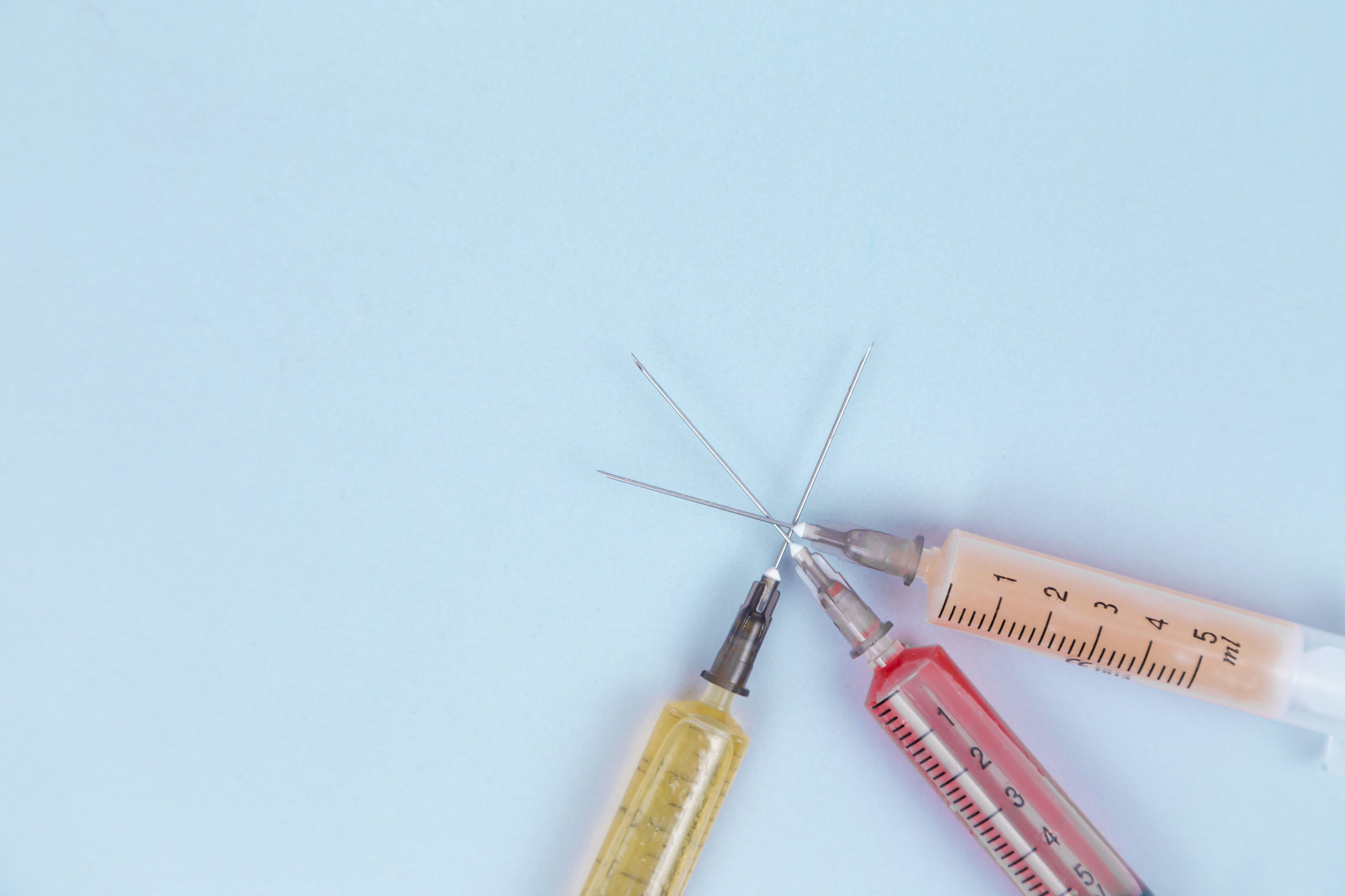 Three syringes with different colored liquids overlap.