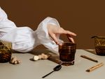 hand with puffy white sleeve reaches towards a cup, ginger and cinnamon sticks on the table