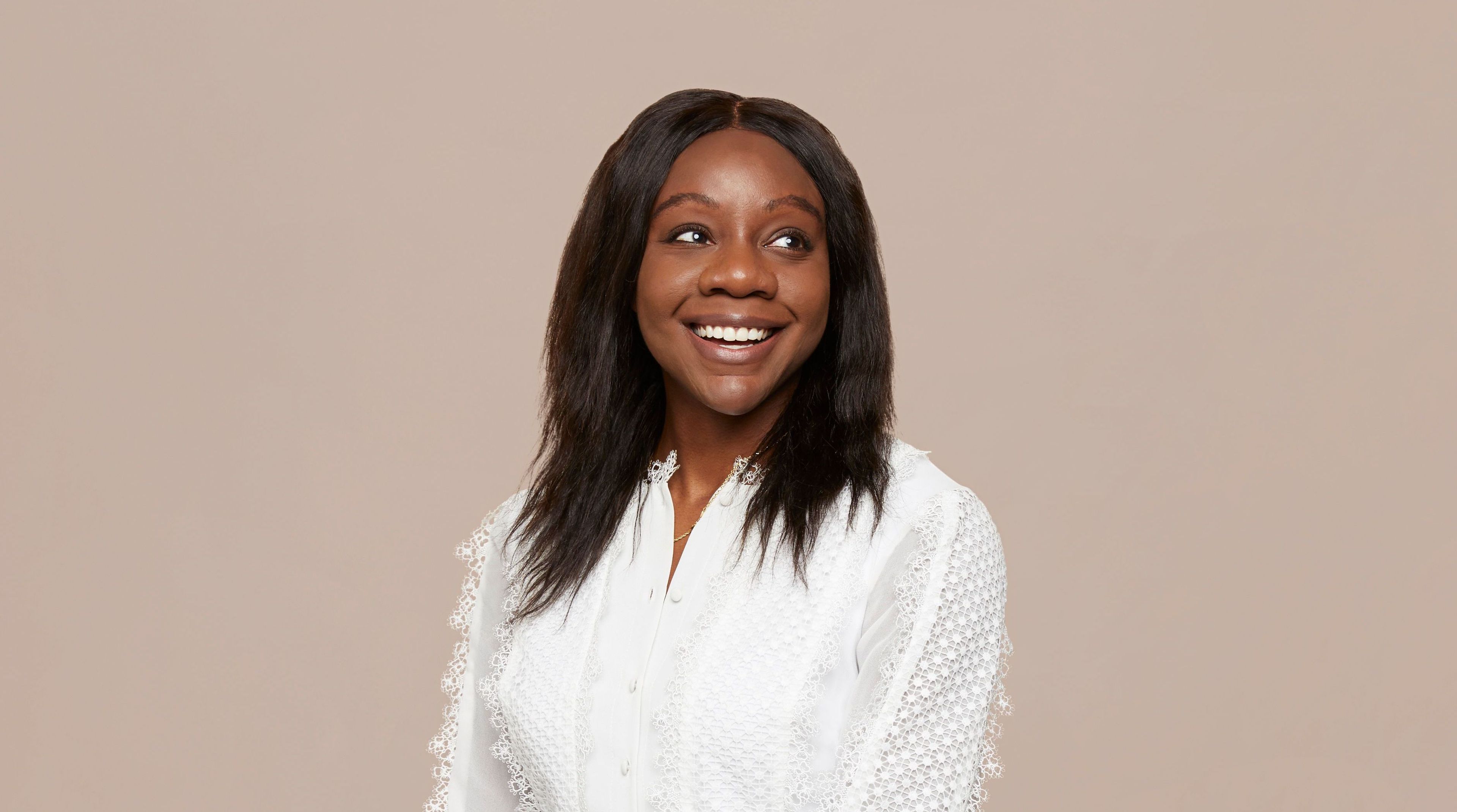 Chika Okoli stands smiling and looking off happily