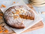 Carrot cake on a wooden cutting board dusted with powdered sugar and sprinkled with almond slivers