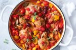 Chicken cacciatore in a white pot on top of a table covered in a white table cloth.