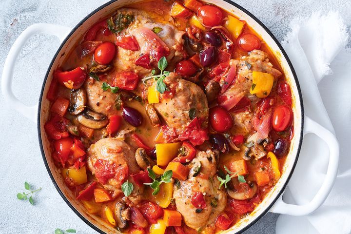 Chicken cacciatore in a white pot on top of a table covered in a white table cloth.