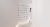A minimalist white curved hallway adorned with metallic crystal-like fixtures arranged in a grid pattern on the wall. A person in white attire with auburn hair is walking through the space, creating an elegant and serene wellness environment.