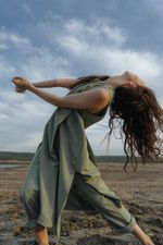 Woman in a green dress dancing on sand