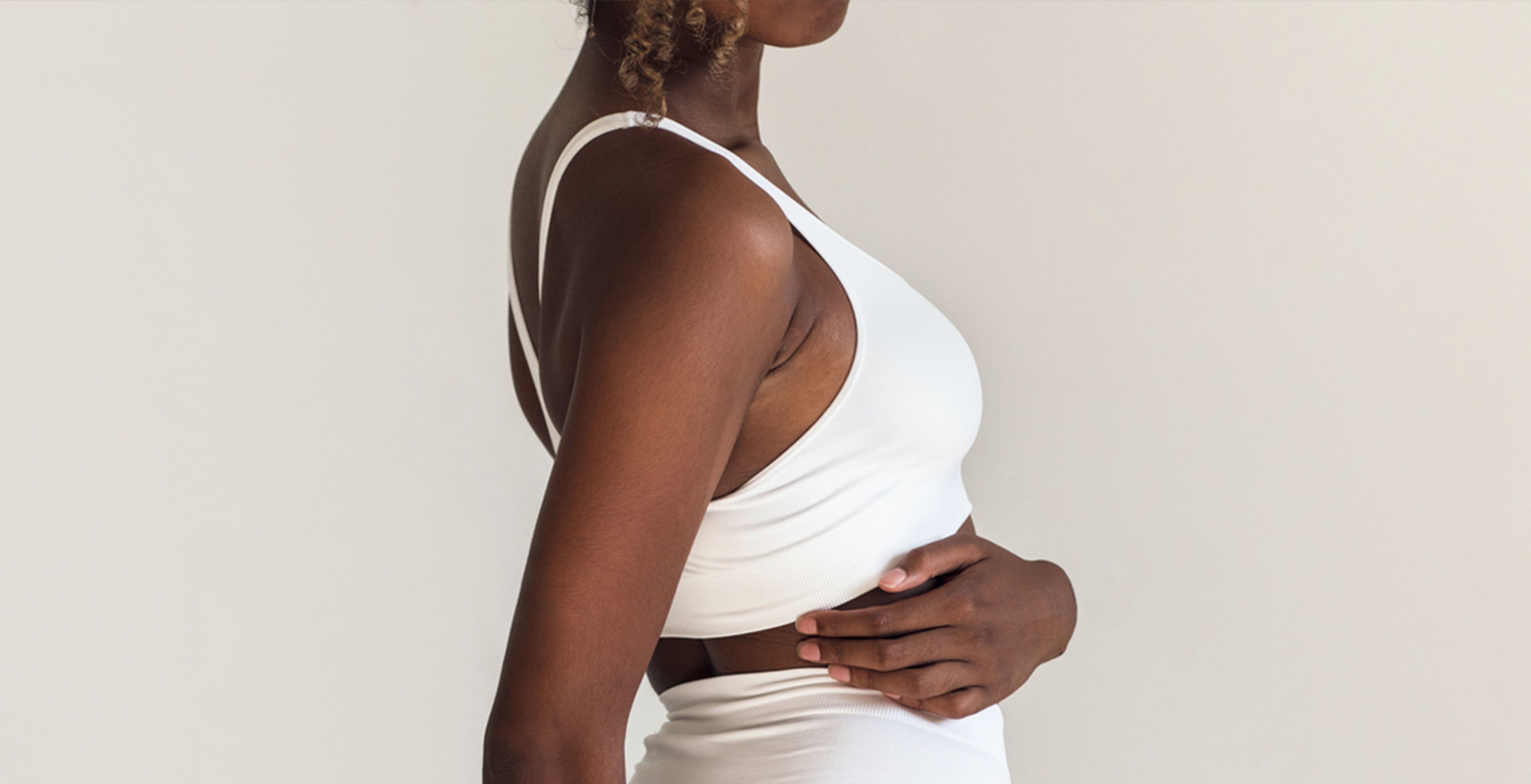 Black woman wraps her arm around herself and holds onto her side