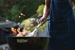 Man standing over a barbecue with a spatula.