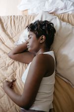 Woman in a white tank top asleep on a bed
