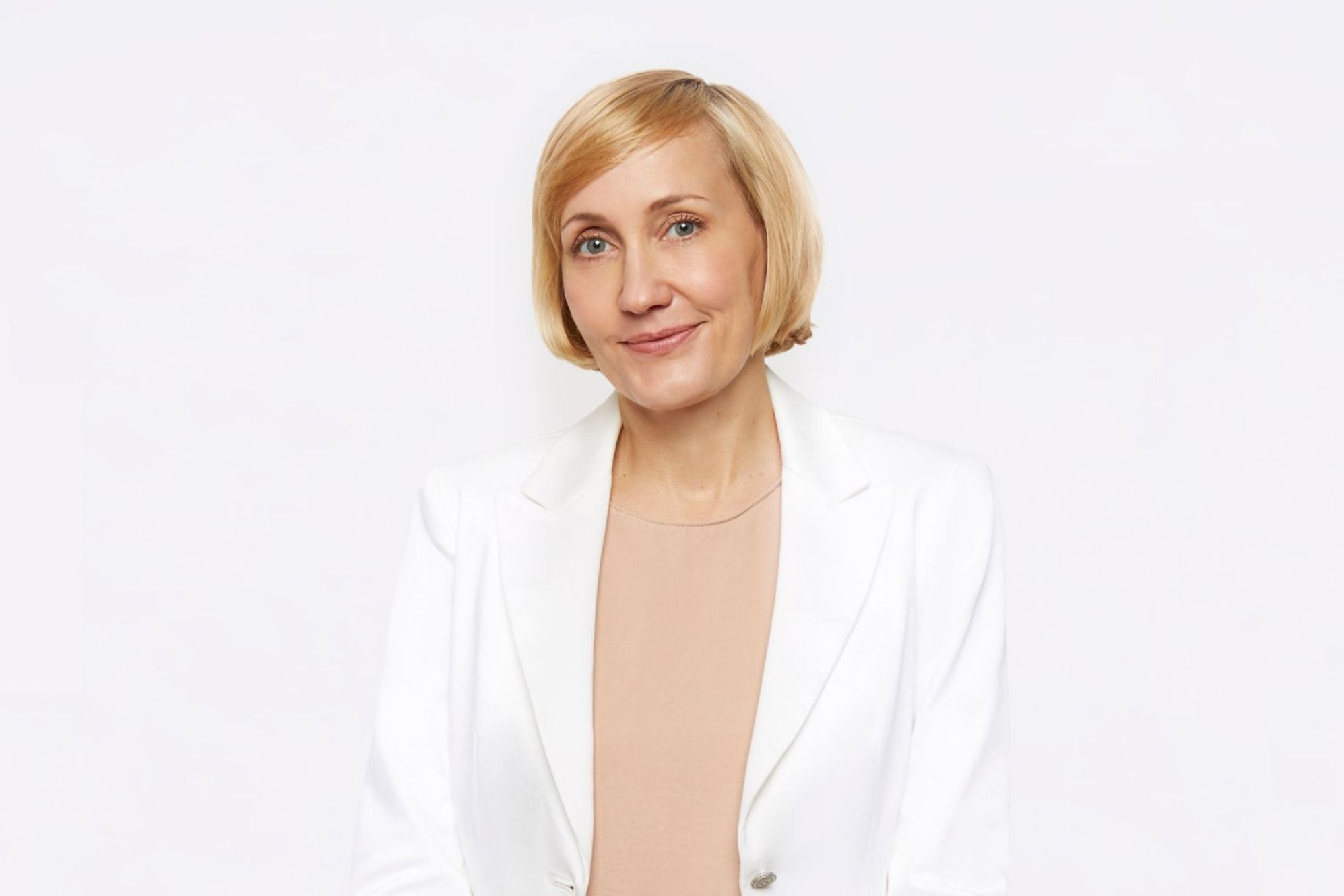 Jessica Sowards, dressed in a white blazer and peach blouse, smiles at the camera.