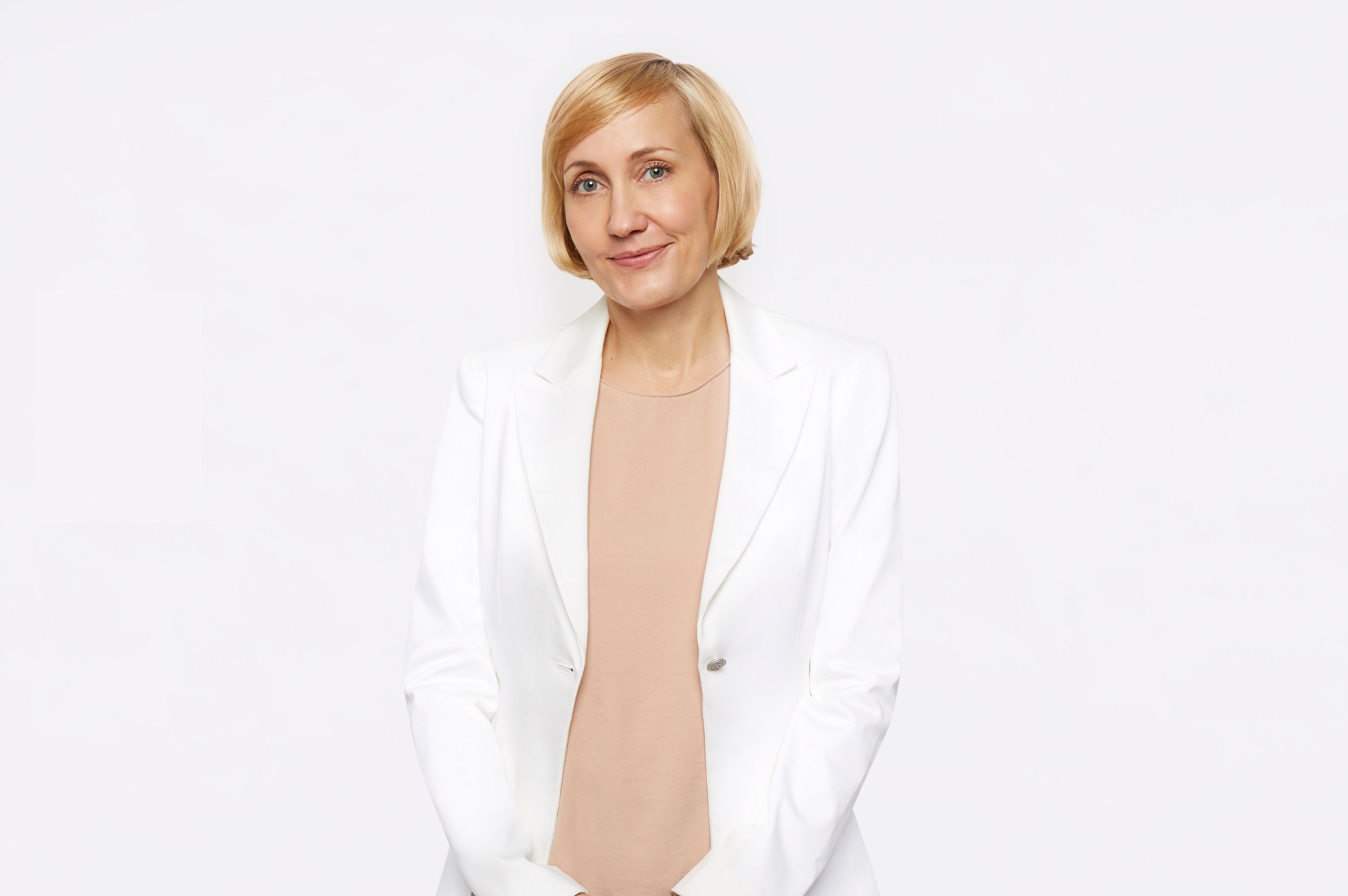 Jessica Sowards, dressed in a white blazer and peach blouse, smiles at the camera.