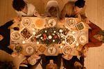 family holding hands around a table set with holiday foods