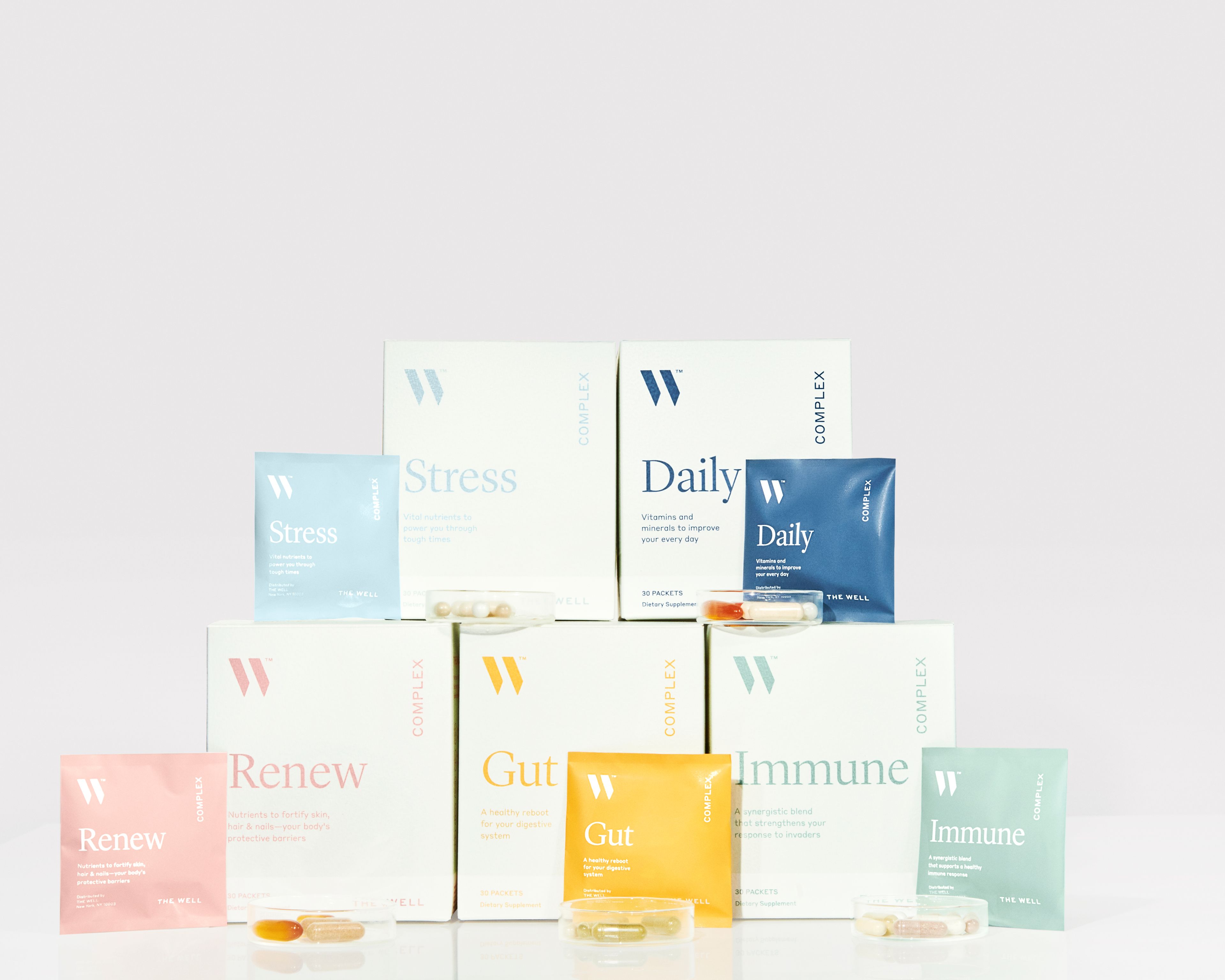 Boxes of THE WELL supplements stacked on top of each other to create a pyramid.