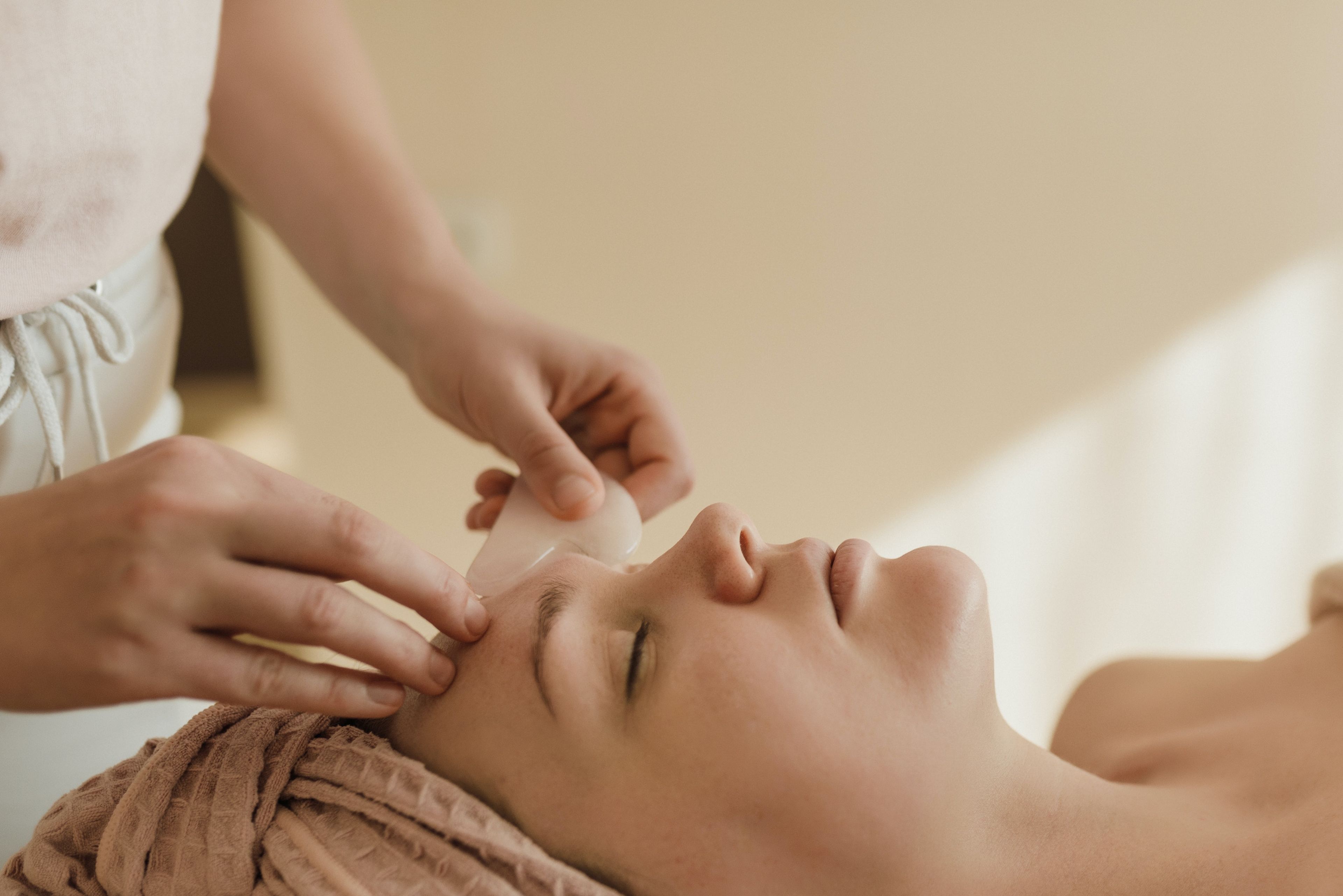 Woman lying on massage table getting a facial gua sha treatment