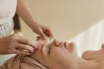 Woman lying on massage table getting a facial gua sha treatment