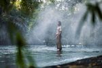 man wades into a river and holds his palms to the water