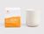 On the left, there is a white rectangular box with a bright orange paint sponge design. An orange THE WELL logo on the top left corner of the box and white text on the orange paint design that reads Sun Salutation, Sweet Orange, Bergamot, Petitgrain, 100% Natural Botanical Candle, 11 oz/312 g. On the right of the box is a cream-colored candle vessel.