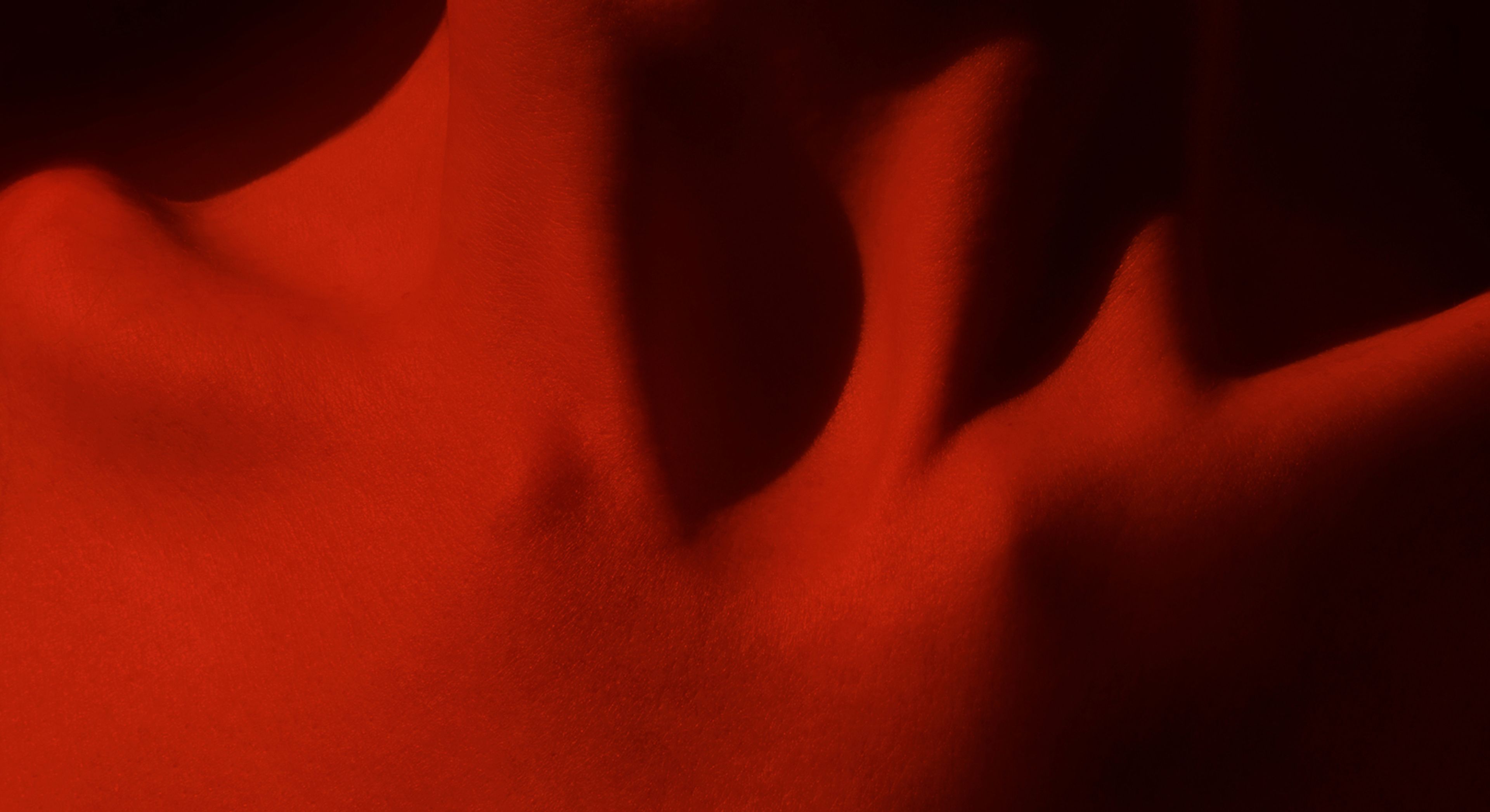 Close up of woman's clavicle with red light reflecting off the body