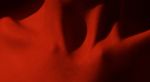 Close up of woman's clavicle with red light reflecting off the body
