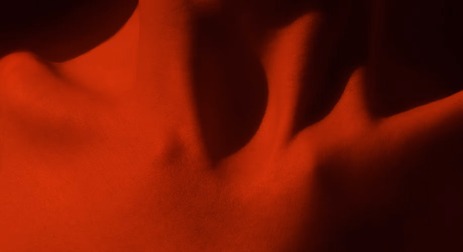 Close up of woman's clavicle with red light reflecting off the body