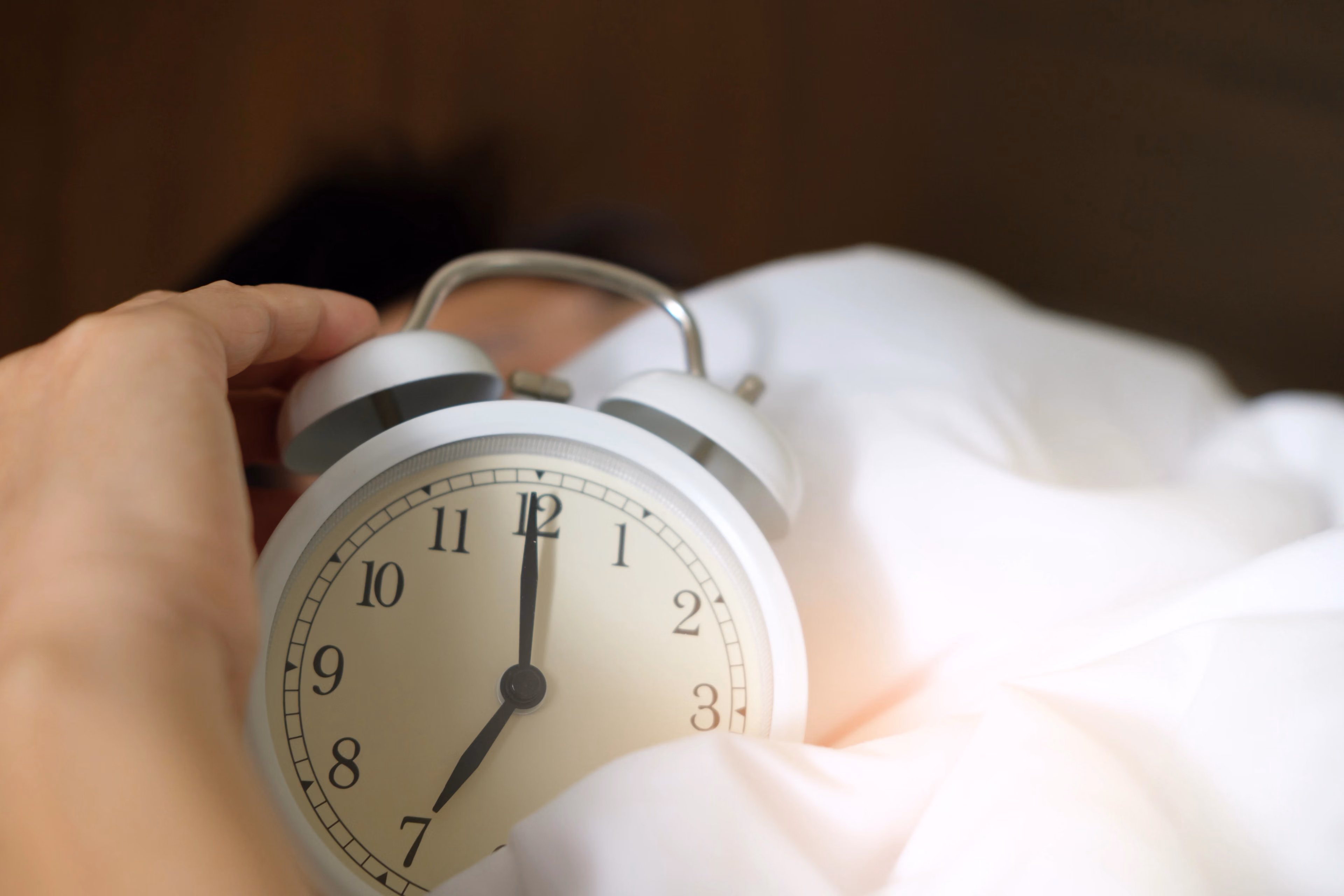 Hand reaches for an alarm clock