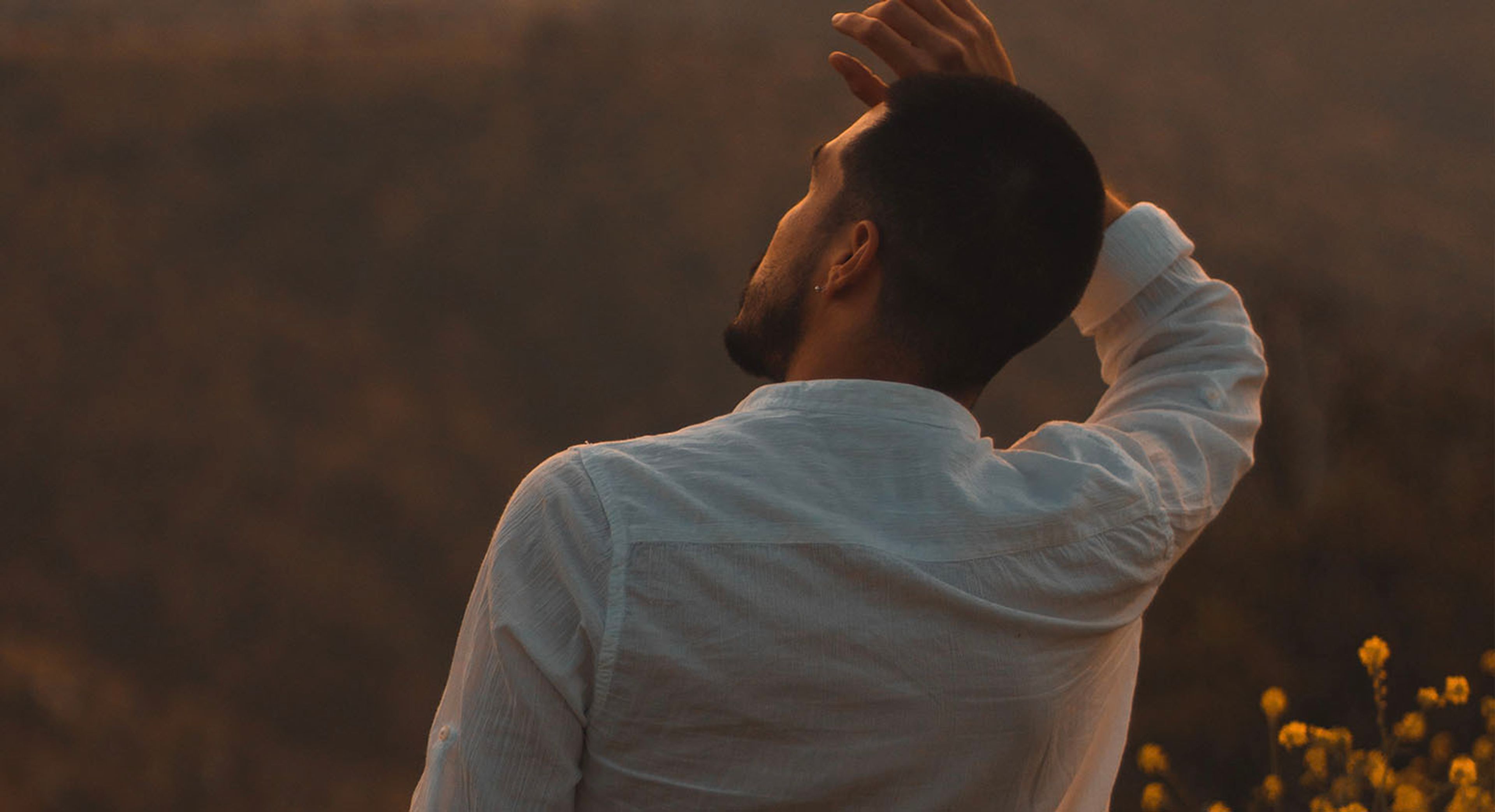 View from behind of a man with hand on his head 