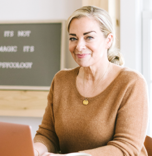 Terri Cole sits at her laptop and smiles.