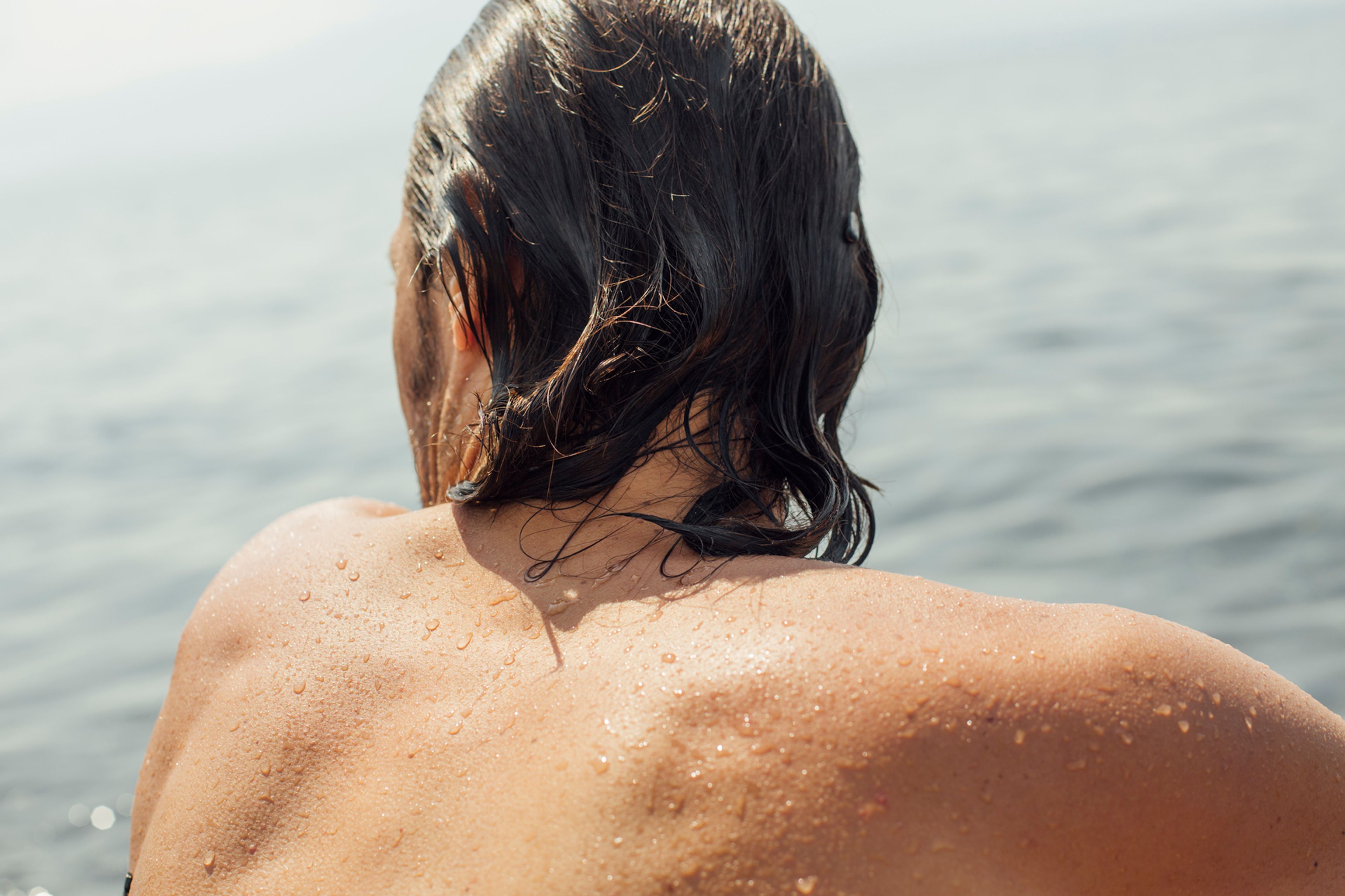 A man with wet hair looking outward over the water