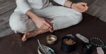 Cross-legged person sits with bowls on the floor in front of them.