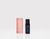 On the left, there is a rose pink rectangular box that reads in white font, Pause, breathe, balance and reset Essential Oil Blend, Bergamot Mint Ylang Ylang, THE WELL logo and 10ml / .33 oz. On the right, there is a dark-tinted bottle with a navy label that reads, reset Essential Oil Blend, Bergamot Mint Ylang Ylang, THE WELL logo, 10ml / .33 oz.  