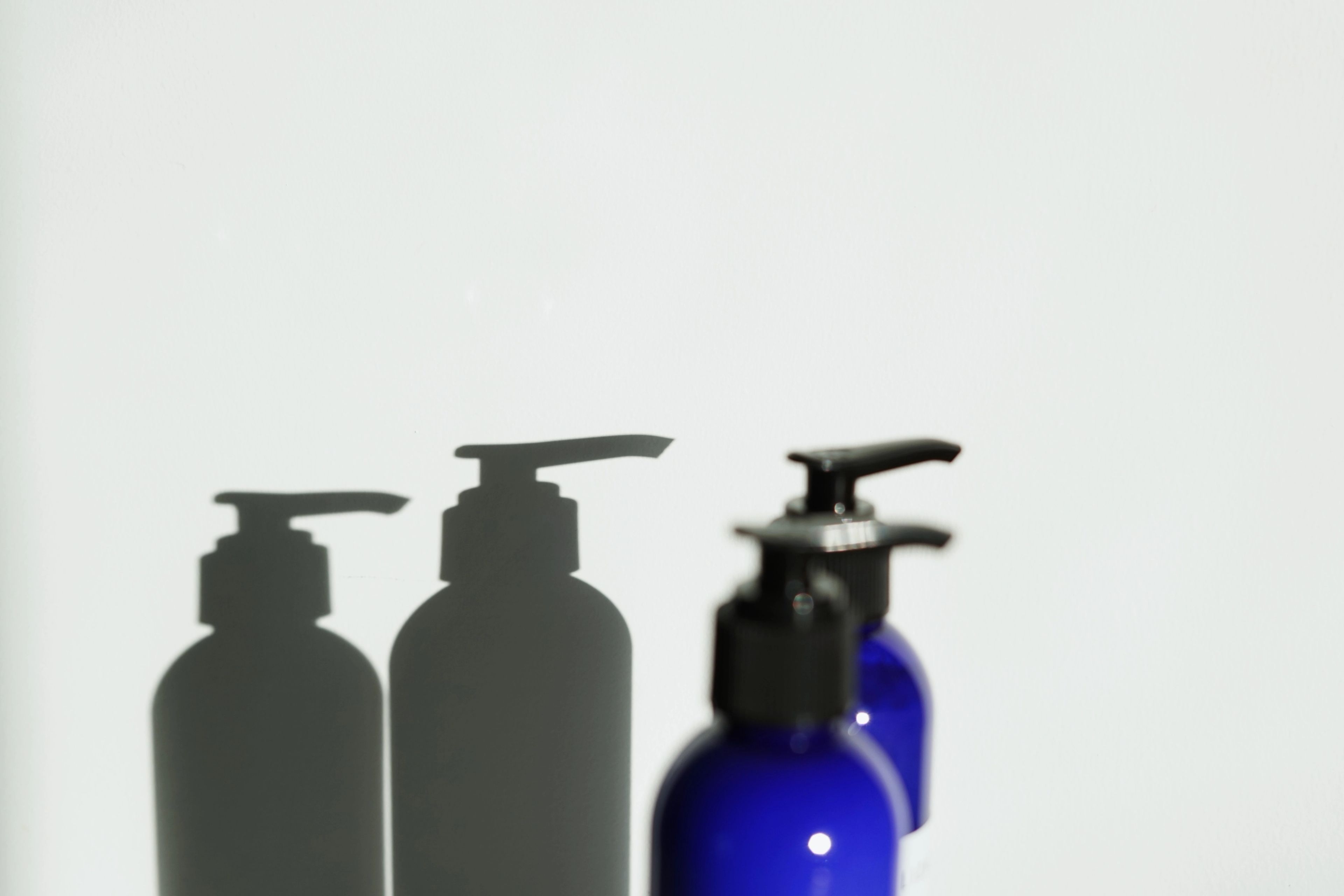Blue plastic bottles with a shadow on the wall behind them
