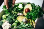 Bowl full of green veggies including avocado, asparagus, herbs, green pepper and broccoli 