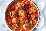 Chicken cacciatore in a white pot on top of a table covered in a white table cloth.