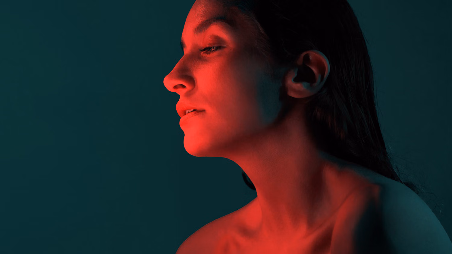 A woman's face glows in a red light.