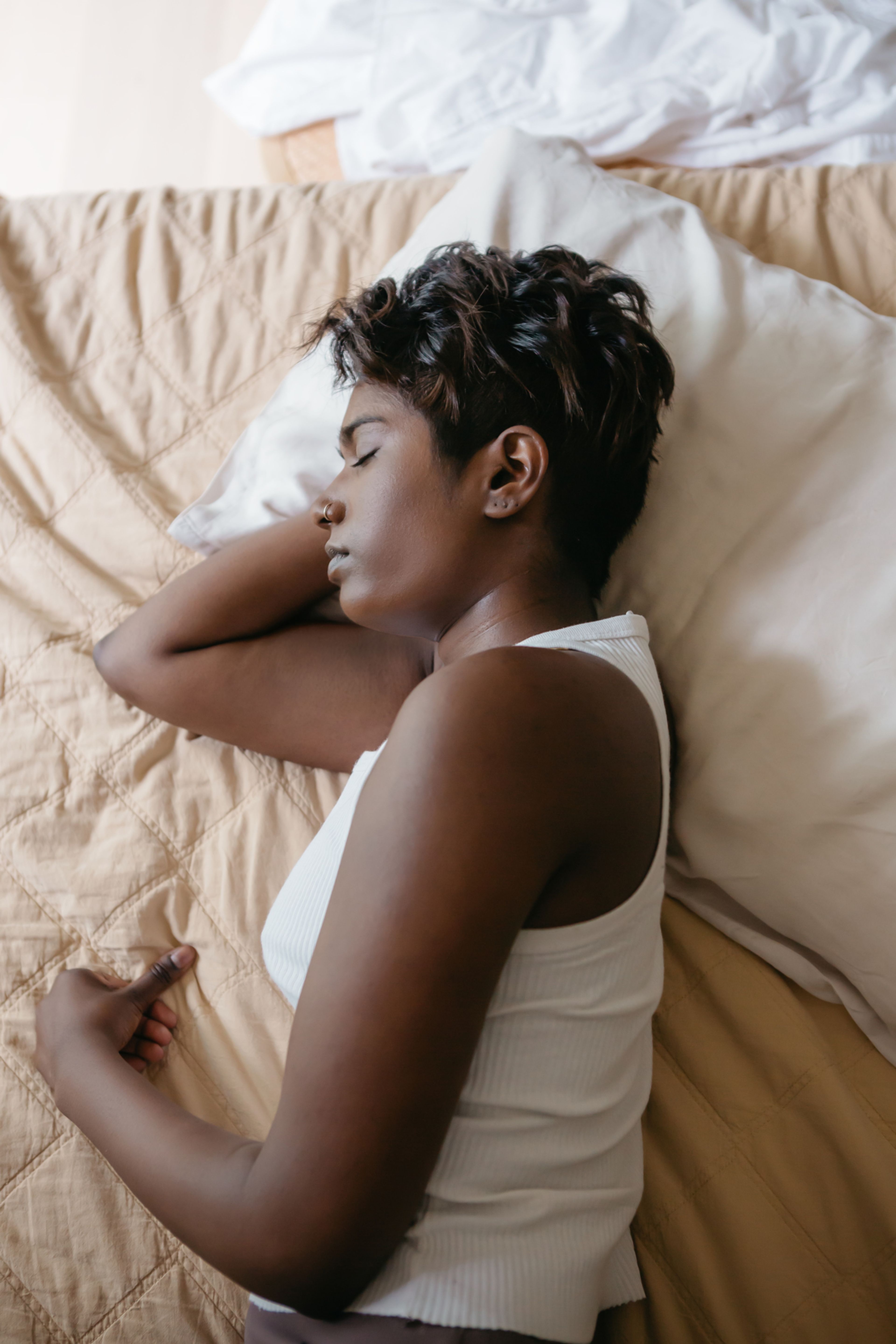 Woman in a white tank top asleep on a bed