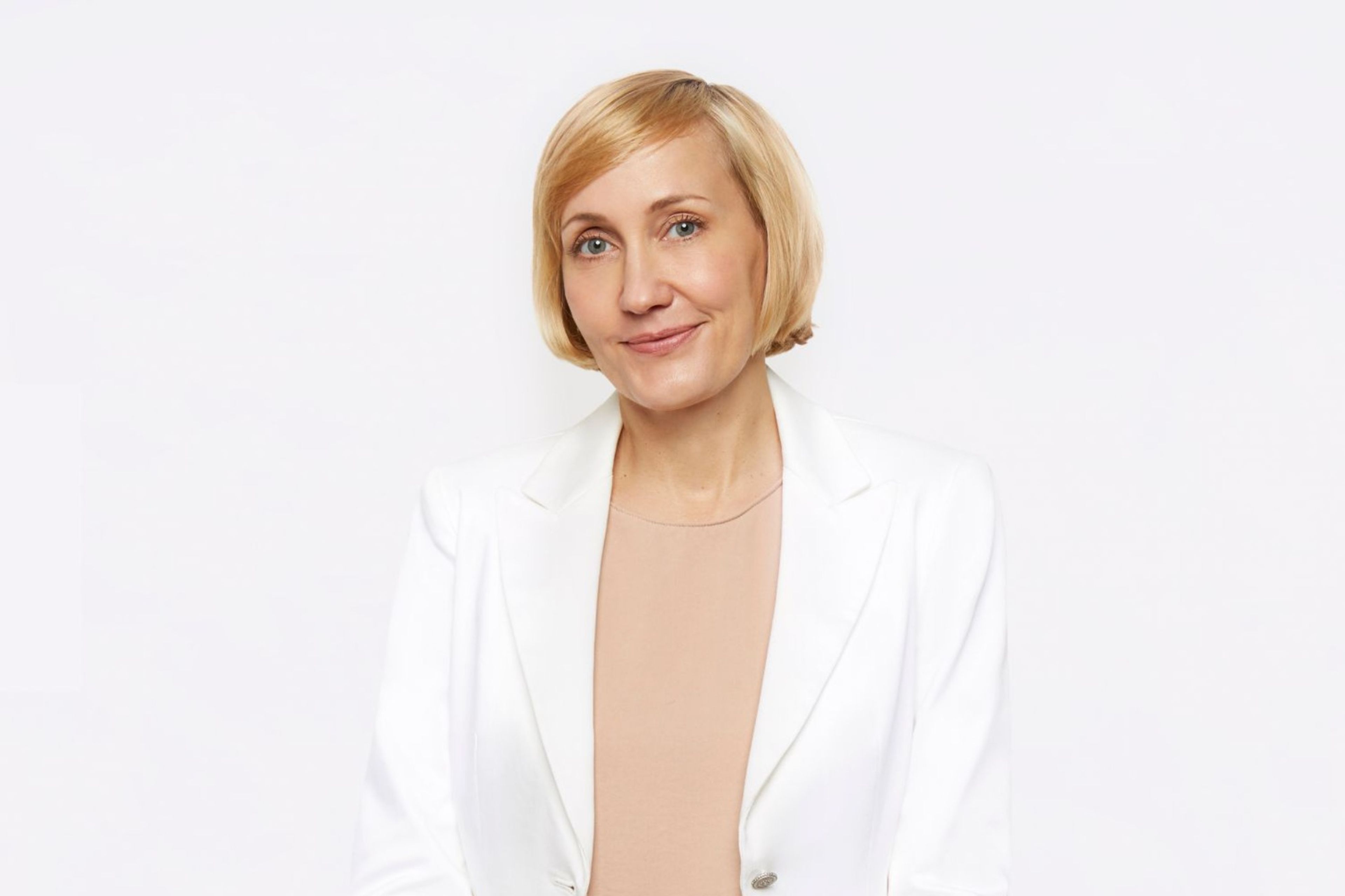 Jessica Sowards, dressed in a white blazer and peach blouse, smiles at the camera.