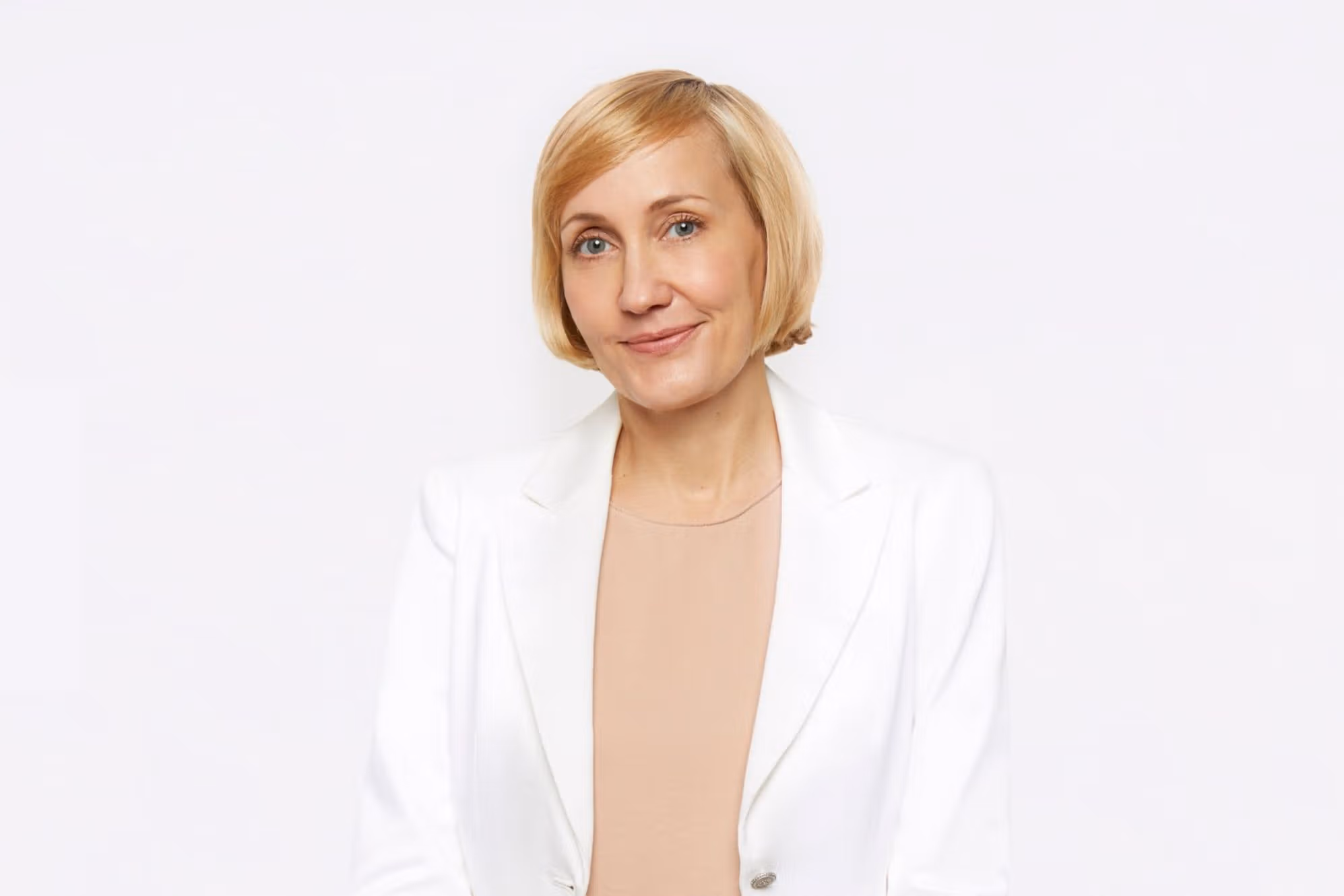 Jessica Sowards, dressed in a white blazer and peach blouse, smiles at the camera.