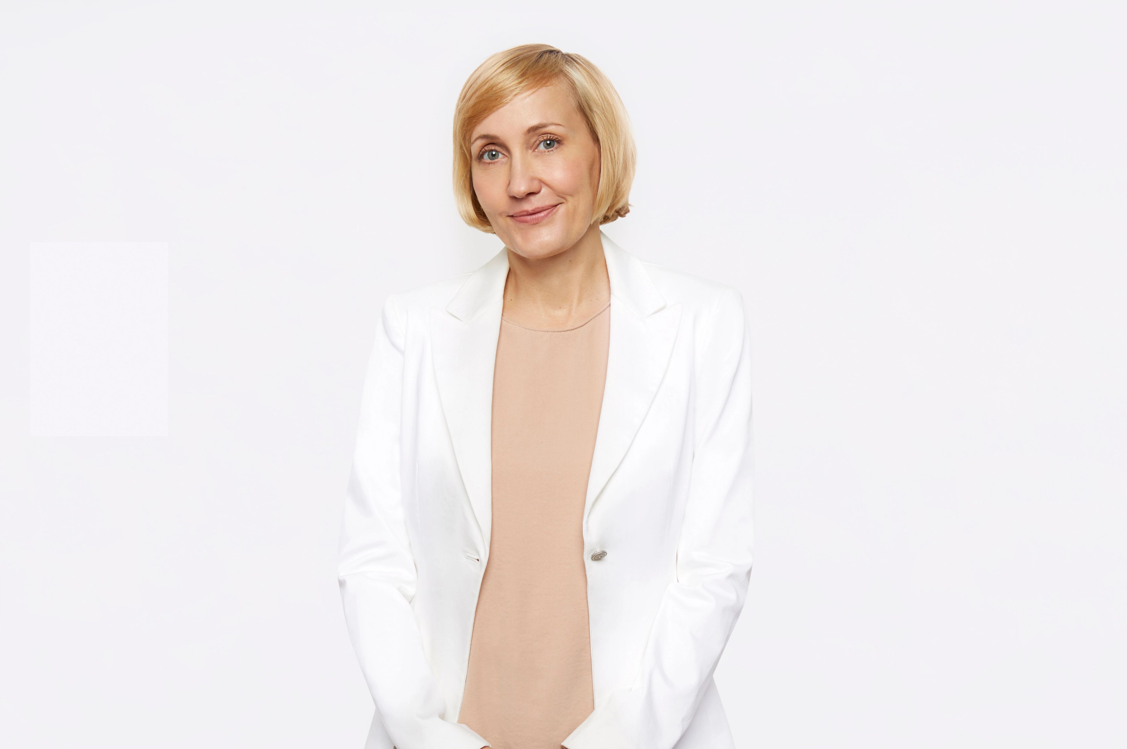 Jessica Sowards, dressed in a white blazer and peach blouse, smiles at the camera.