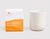 On the left, there is a white rectangular box with a bright orange paint sponge design. An orange THE WELL logo on the top left corner of the box and white text on the orange paint design that reads Sun Salutation, Sweet Orange, Bergamot, Petitgrain, 100% Natural Botanical Candle, 11 oz/312 g. On the right of the box is a cream-colored candle vessel.